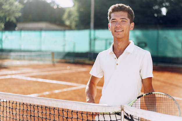 Joven jugador de tenis de raza mixta con pie de raqueta en la cancha de tenis