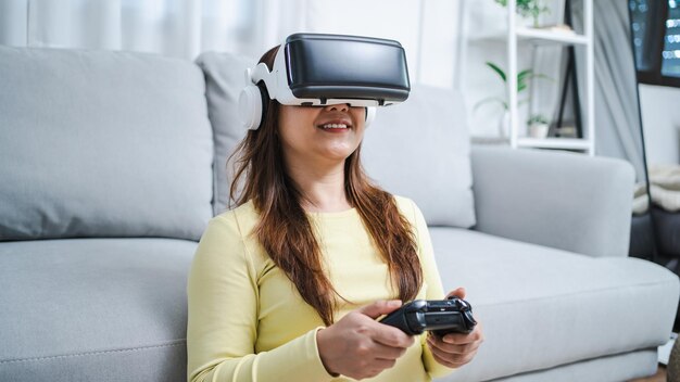 Joven jugadora asiática con realidad virtual tocando el aire durante la experiencia de realidad virtual Futuro jugador de tecnología doméstica hobby concepto de disfrute lúdico