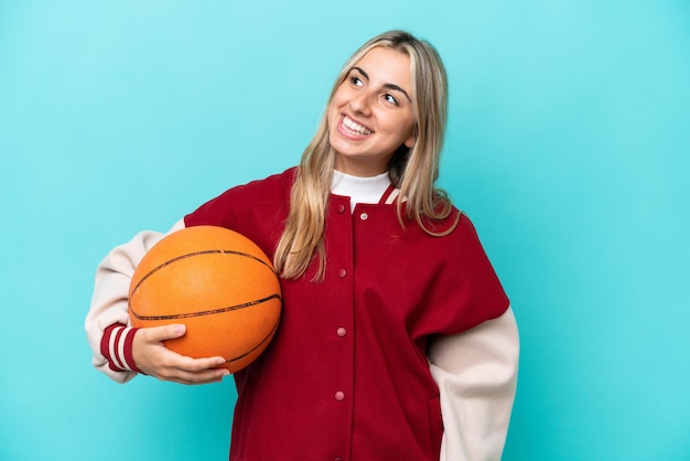 Joven jugadora de baloncesto caucásica aislada de fondo azul pensando en una idea mientras mira hacia arriba