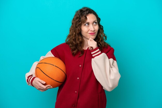 Foto joven jugadora de baloncesto caucásica mujer aislada de fondo azul y mirando hacia arriba