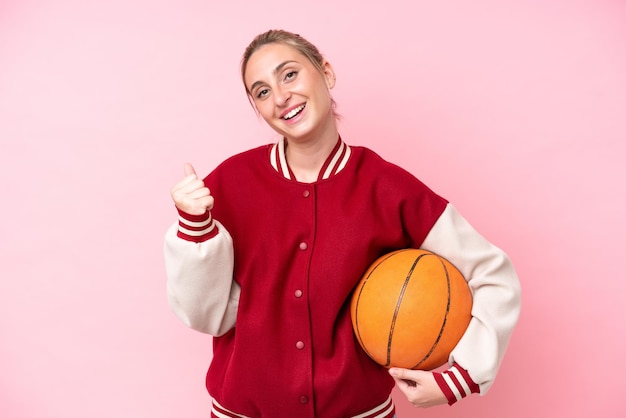 Joven jugadora de baloncesto caucásica mujer aislada de fondo rosa celebrando una victoria