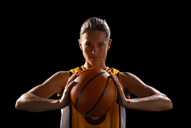 Foto una joven jugadora de baloncesto caucásica posa con confianza con ropa de baloncestro sobre un fondo negro