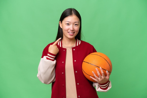 Joven jugadora de baloncesto mujer asiática sobre un fondo aislado dando un gesto de pulgar hacia arriba