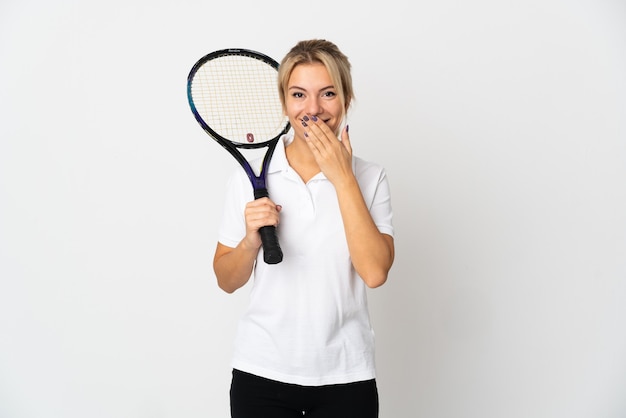 Joven jugadora de tenis rusa aislada en blanco feliz y sonriente cubriendo la boca con la mano