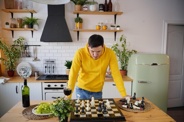 Joven jugando al ajedrez en la mesa de la cocina