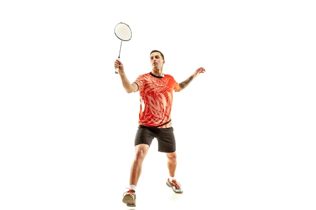 Joven jugando al bádminton sobre fondo blanco de estudio. Ajuste atleta masculino aislado en blanco. jugador de bádminton en acción, movimiento, movimiento. concepto de ataque y defensa