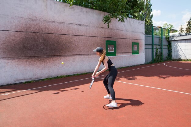 Una joven jugando al tenis en la pared es un deporte profesional.