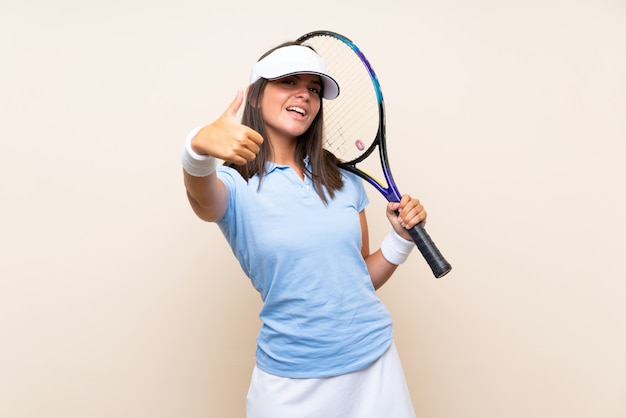 Joven jugando al tenis sobre una pared aislada con los pulgares arriba porque algo bueno ha sucedido