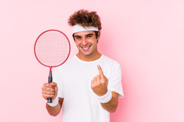 Joven jugando bádminton aislado apuntando con el dedo como si invitara a acercarse.