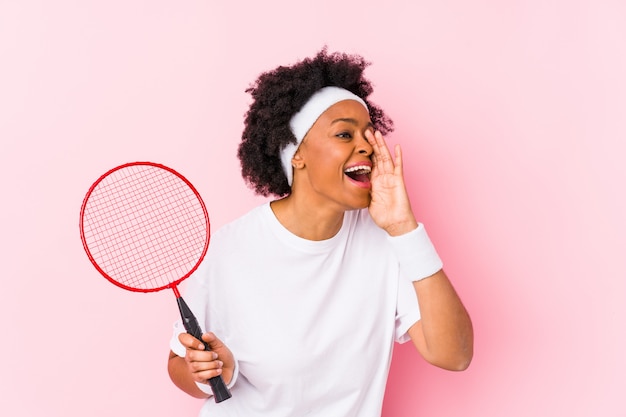 Joven jugando bádminton gritando y sosteniendo la palma cerca de la boca abierta