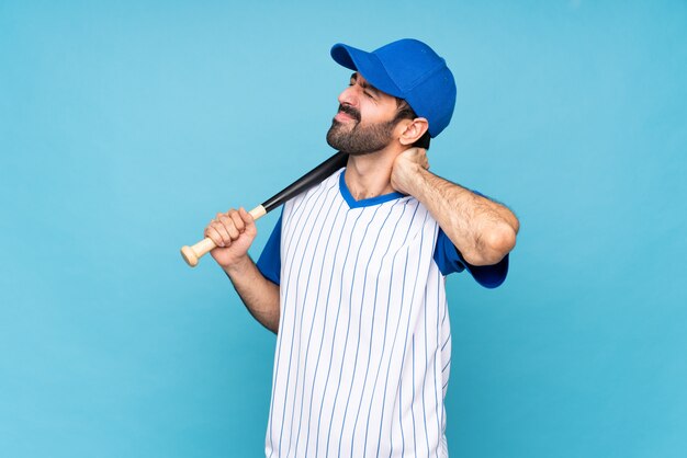 Joven jugando béisbol sobre pared azul aislada con dolor de cuello