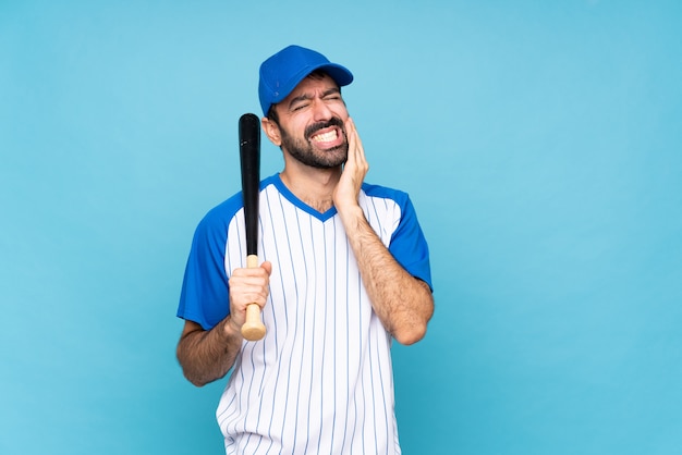 Joven jugando béisbol sobre pared azul aislado con dolor de muelas