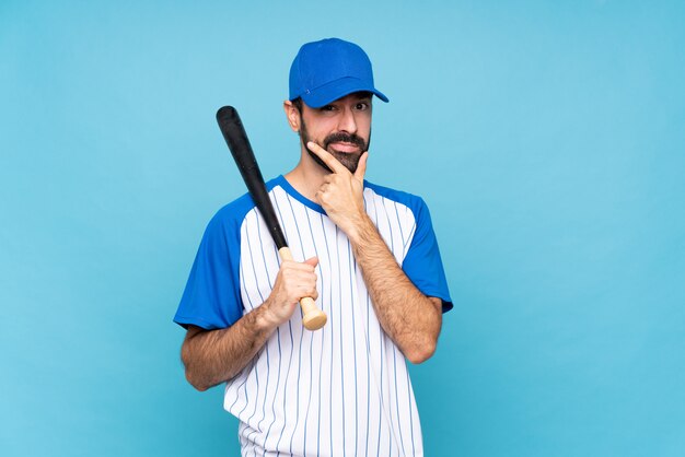 Joven jugando béisbol sobre pensamiento de pared azul aislado