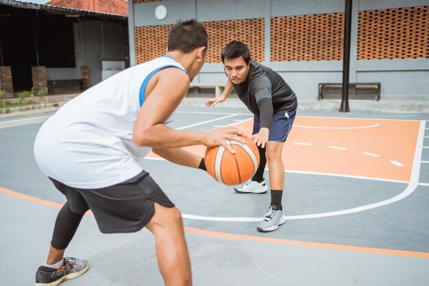 Foto joven jugando con la pelota en la cancha de baloncesto