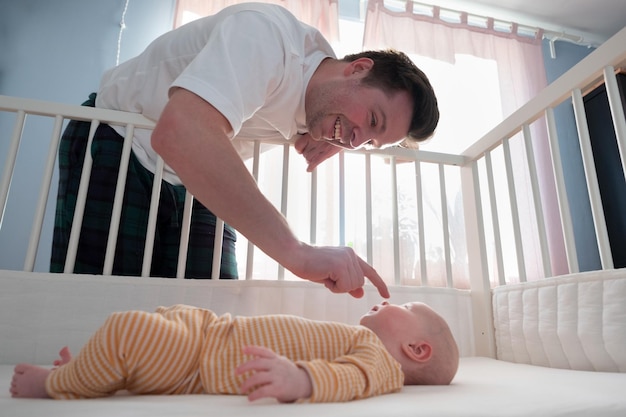 Joven jugando con su pequeño bebé en la cama