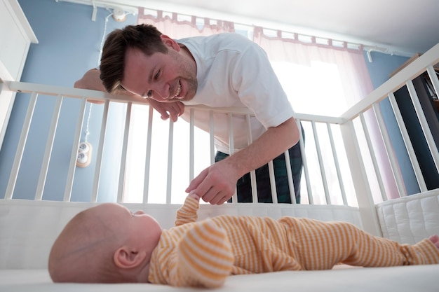 Joven jugando con su pequeño bebé en la cama