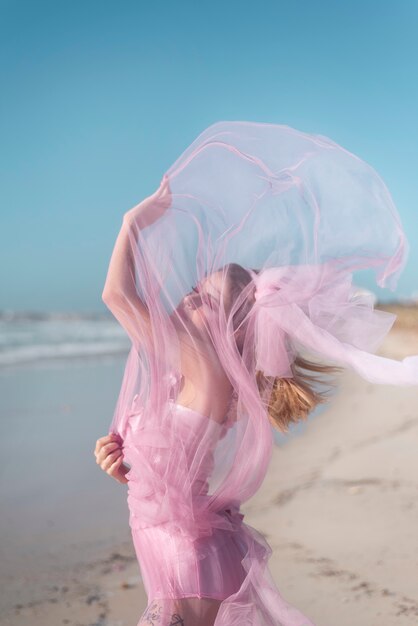 Joven jugando con un vestido rosa que se mueve por el viento