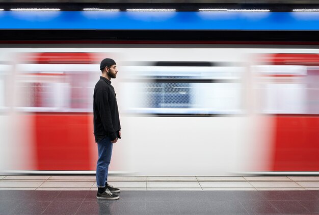 Foto joven de lado con una máscara en la plataforma del metro