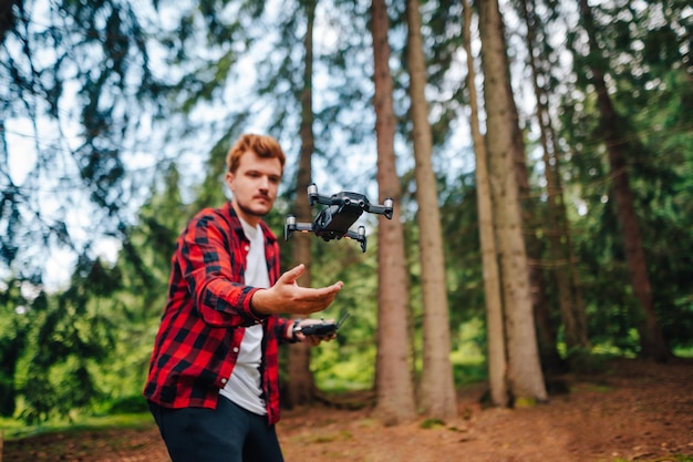 joven lanza un dron en el bosque con las manos