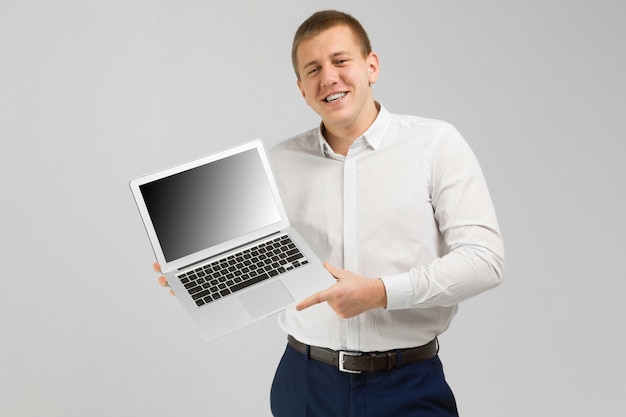 Joven con laptop con una pantalla vacía en sus manos está aislado sobre fondo claro