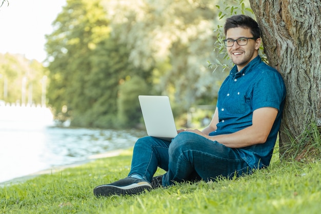 Joven con laptop sentada al aire libre en el césped