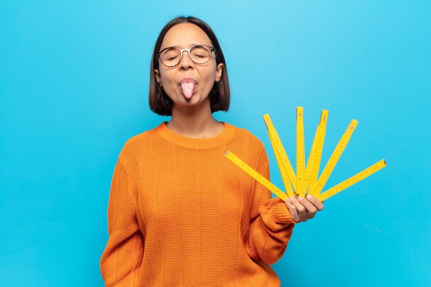 Joven latina con actitud alegre, despreocupada y rebelde, bromeando y sacando la lengua, divirtiéndose