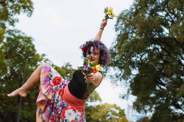 Joven latina bailando en el parque con falda colorida y maquillaje La Calavera Catrina