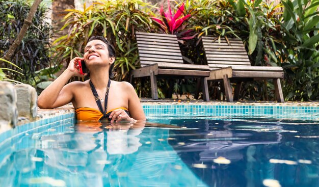 Una joven latina disfrutando de un momento sereno en una piscina natural turquesa en un tranquilo complejo