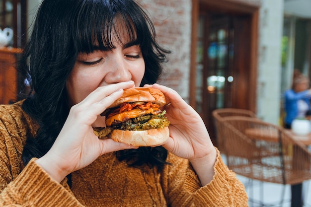 joven latina disfrutando de su hamburguesa