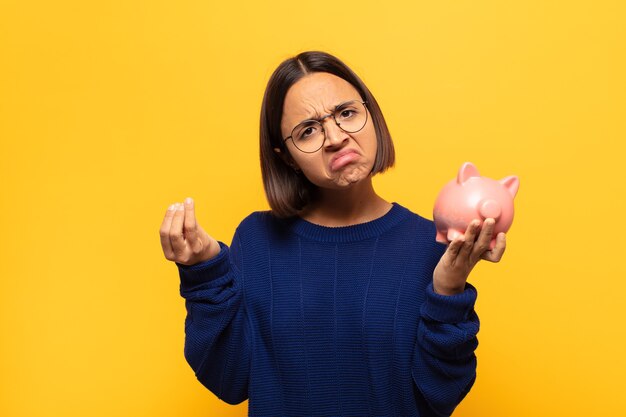 Joven latina haciendo capice o gesto de dinero, ¡diciéndole que pague sus deudas!