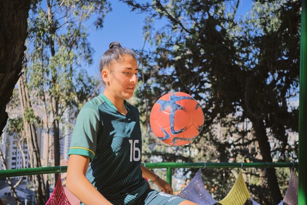 Foto joven latina practicando fútbol en un parque en bolivia américa latina