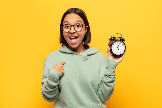 Joven latina que se siente feliz, sorprendida y orgullosa, señalando a sí misma con una mirada emocionada y asombrada