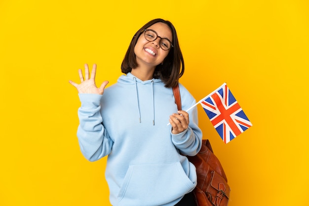 Joven latina sosteniendo una bandera de Reino Unido aislada
