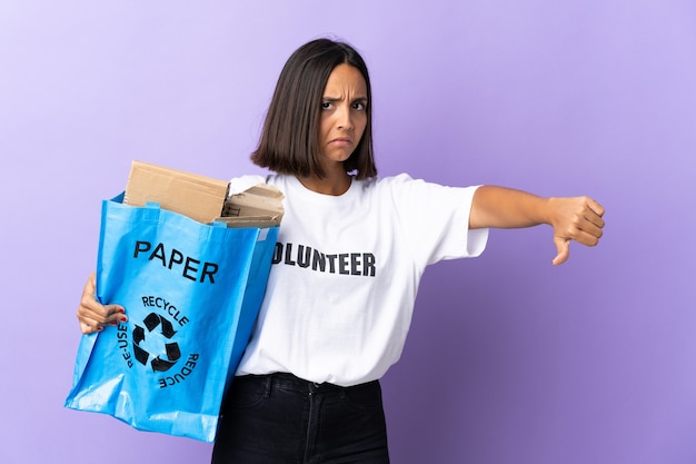 Joven latina sosteniendo una bolsa de reciclaje llena de papel para reciclar aislado