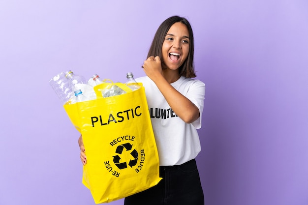 Joven latina sosteniendo una bolsa de reciclaje llena de papel para reciclar