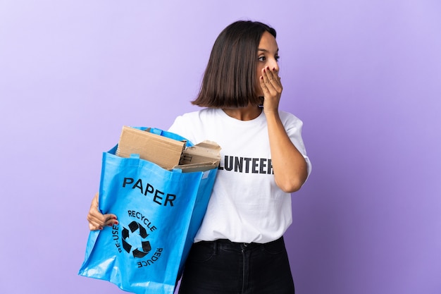 Joven latina sosteniendo una bolsa de reciclaje llena de papel para reciclar