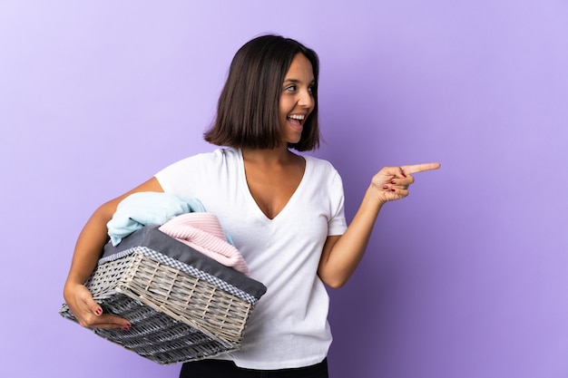 Joven latina sosteniendo una canasta de ropa aislada