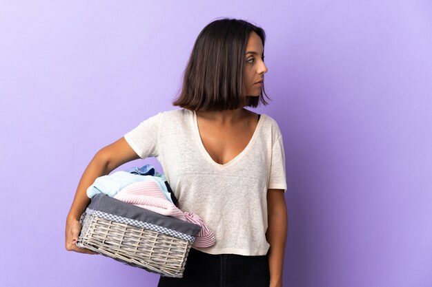 Foto joven latina sosteniendo una canasta de ropa aislada