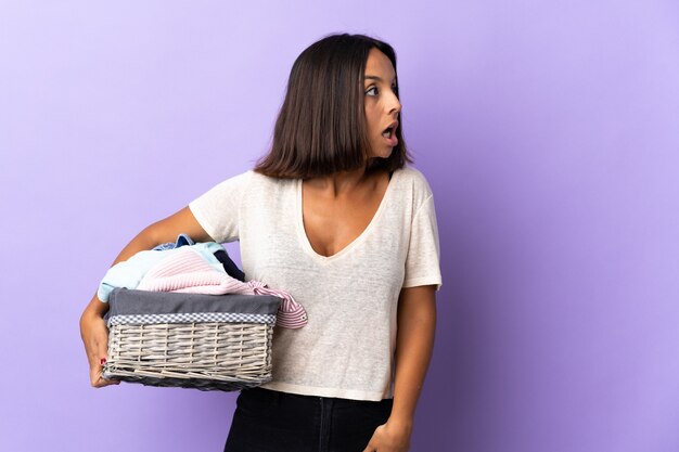 Joven latina sosteniendo una canasta de ropa