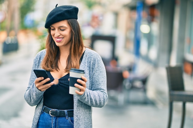 Joven latina usando un teléfono inteligente tomando café en la ciudad.