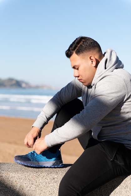 Joven latino atando cordones antes de entrenar. Enfoque y determinación en el concepto deportivo.