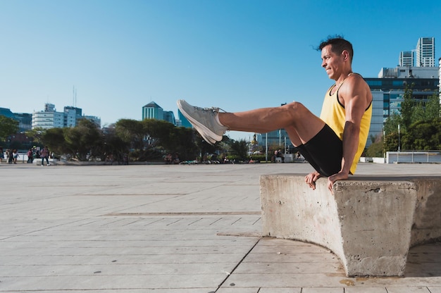 Joven latino entrenando al aire libre haciendo sentadillas en un banco