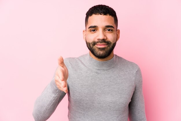 Joven latino estirando la mano a la cámara en gesto de saludo