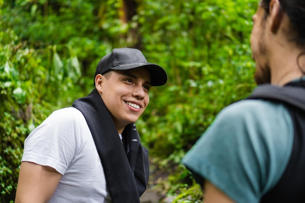 Joven latino en la jungla sonriendo mientras habla con su compañero de caminata