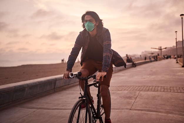 Joven latino monta una bicicleta durante una hermosa puesta de sol