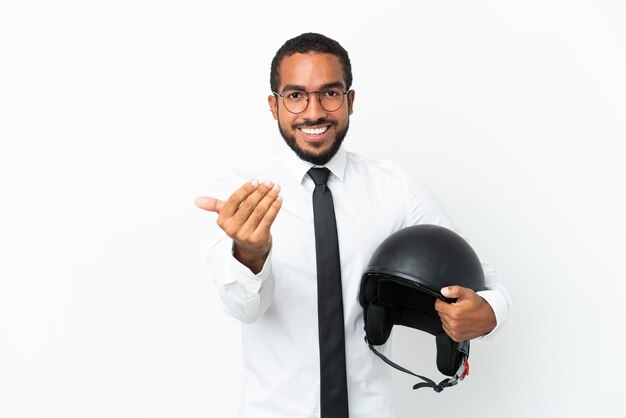 Joven latino de negocios con casco de motocicleta aislado de fondo blanco invitando a venir con la mano Feliz de que hayas venido