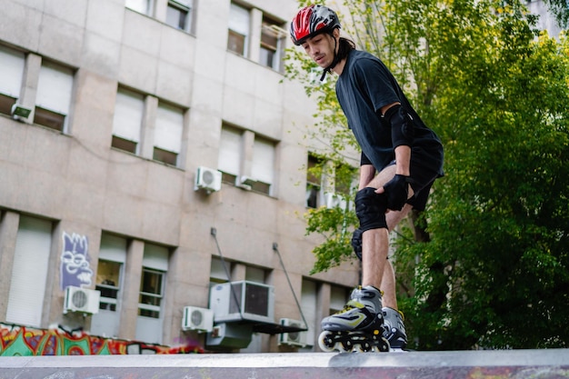 Joven latino en un parque de patinaje montando rodillos con todas las protecciones tomando una decisión copiando espacio