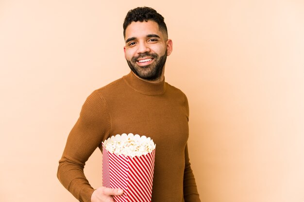 Joven latino sosteniendo un cubo de palomitas de maíz mira a un lado