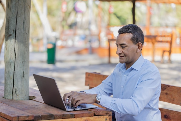 Joven latino usando una computadora portátil al aire libre