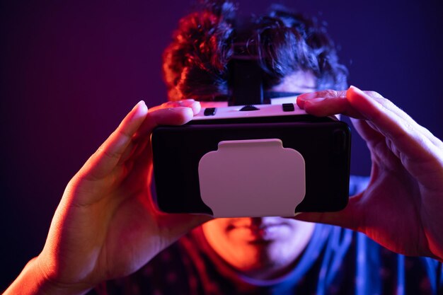 Joven latino usando Realidad Virtual VR Auriculares Gafas 3D Fondo oscuro Clave baja